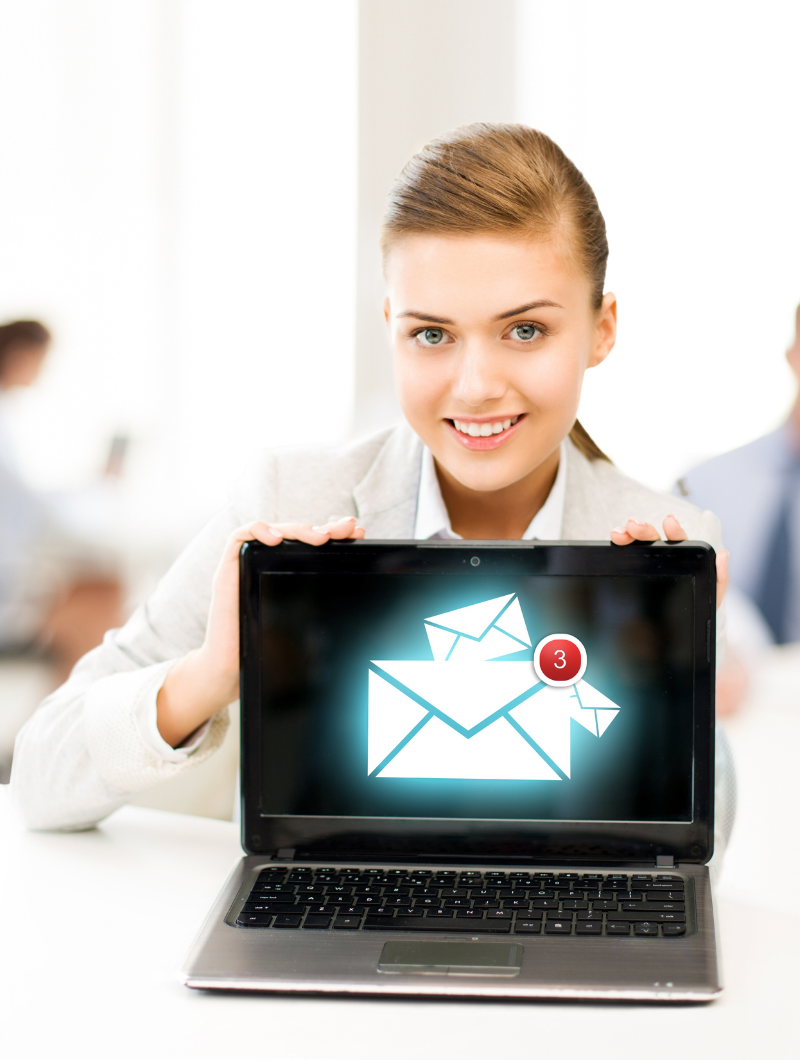 A smiling woman in business attire holding a laptop toward the camera. The laptop screen shows a graphic of multiple envelope icons with a red notification bubble indicating 3 new messages. The background is a bright office setting with blurred figures.