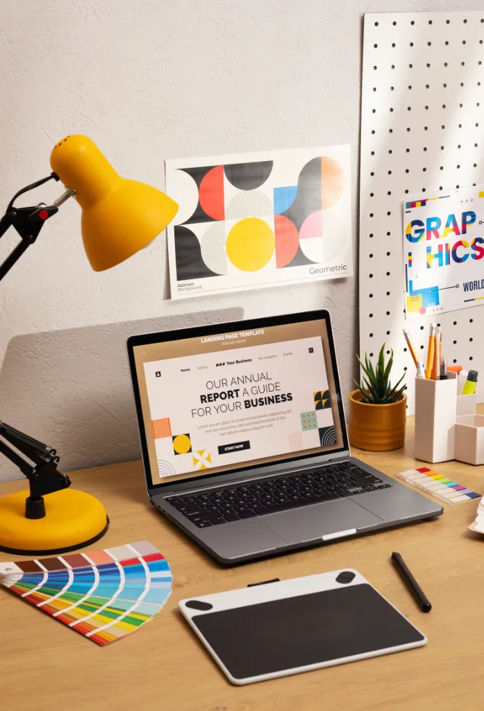 An overhead view of a workspace with a computer displaying a creative concept of 'Potential' featuring words like skill, success, vision, and experience. The workspace includes a color palette, keyboard, and a drawing tablet.
