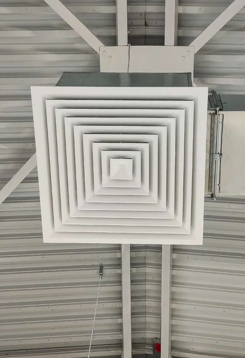 Ceiling air vent with a series of white, concentric square panels, part of an HVAC system.