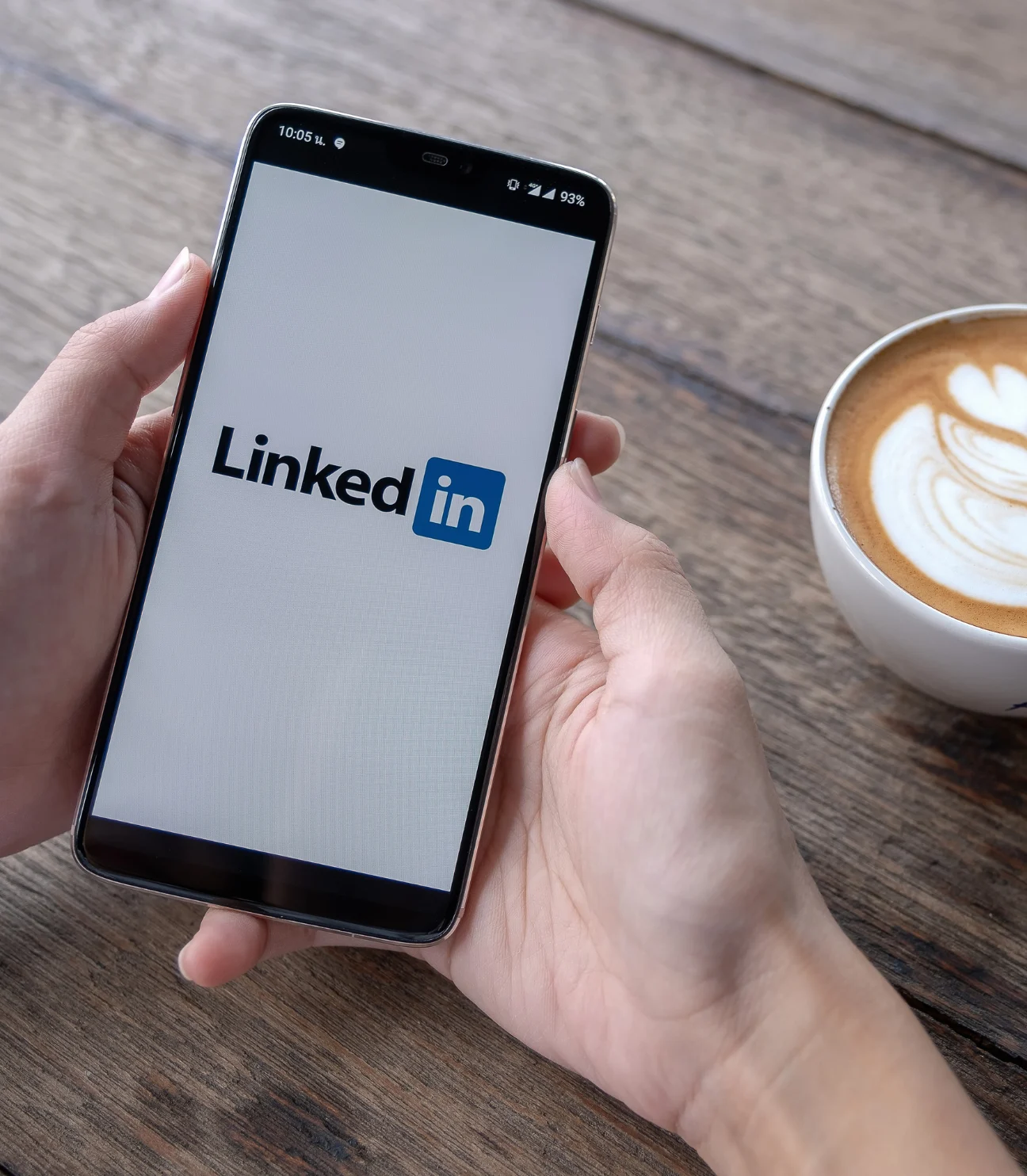 A person holding a smartphone with the LinkedIn login screen visible.